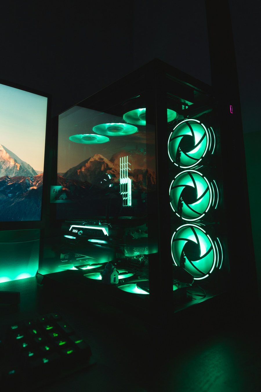 Black tower PC lit green, three front fans glowing