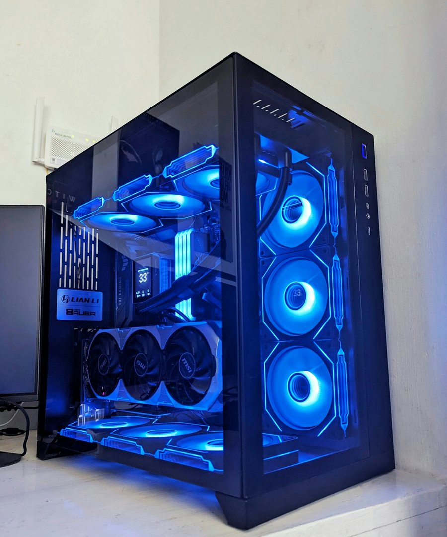 Large glass full-tower PC lit blue, with a triple-fan graphics card inside